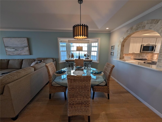 dining area featuring wood-type flooring, a tray ceiling, and crown molding