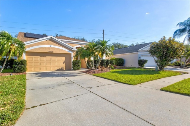 ranch-style home with solar panels, a garage, and a front yard