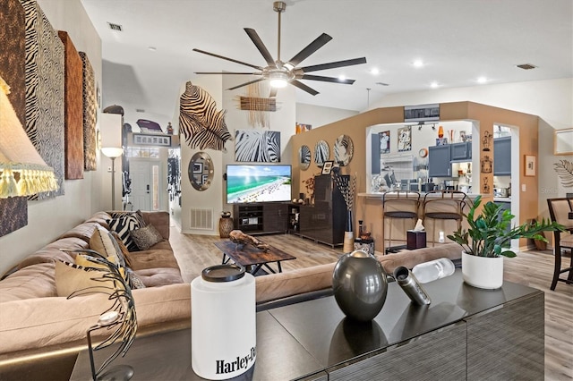 living room featuring ceiling fan, light hardwood / wood-style floors, and vaulted ceiling