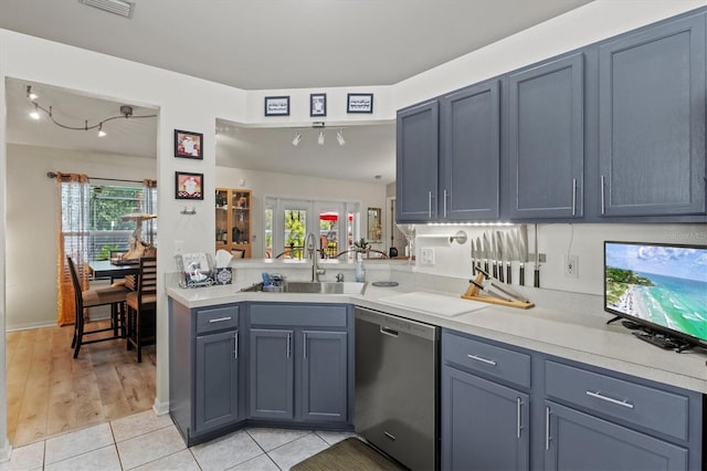 kitchen with sink, light tile patterned floors, stainless steel dishwasher, and blue cabinets