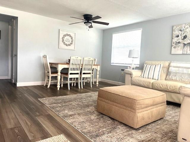 living room with ceiling fan and dark wood-type flooring