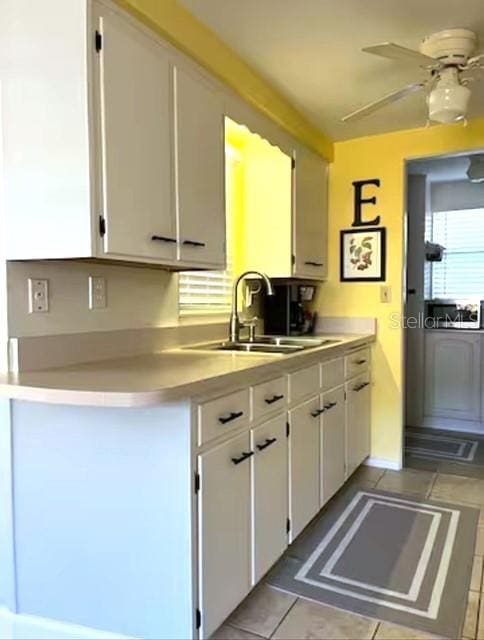 kitchen with ceiling fan, sink, white cabinetry, and light tile patterned floors