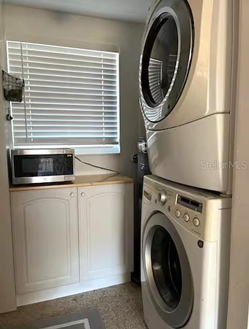 washroom featuring stacked washer / drying machine