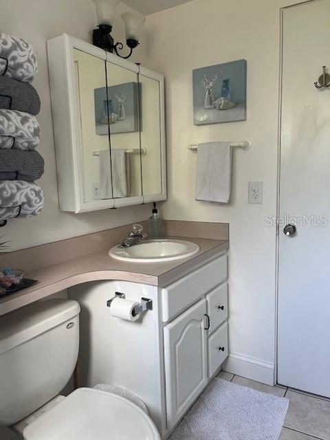 bathroom with toilet, tile patterned flooring, and vanity