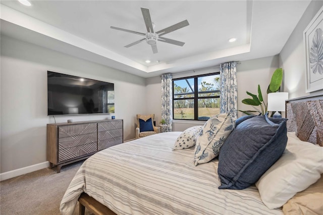 carpeted bedroom with a tray ceiling and ceiling fan