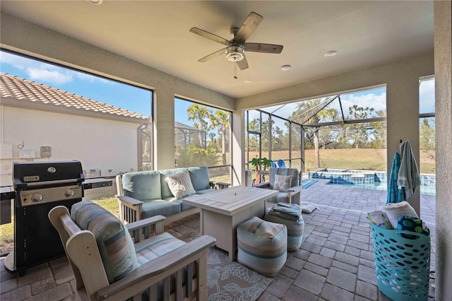 view of patio featuring glass enclosure, ceiling fan, an outdoor hangout area, grilling area, and an in ground hot tub