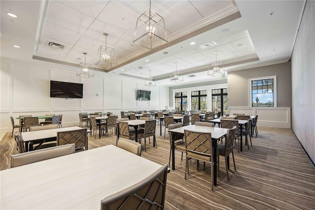 carpeted dining room featuring a raised ceiling and ornamental molding