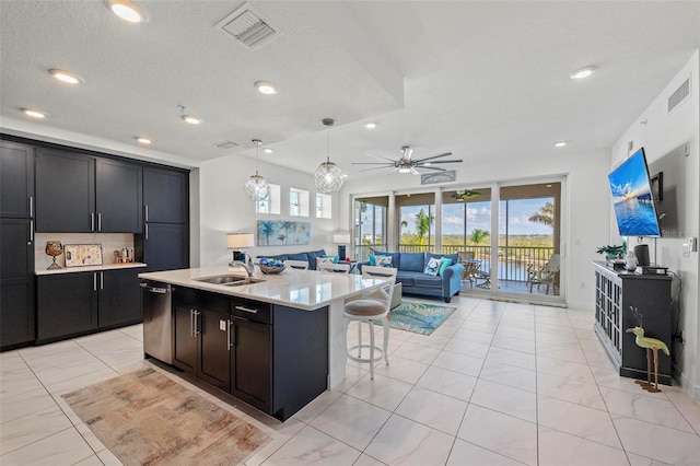 kitchen featuring decorative light fixtures, dishwasher, sink, a kitchen bar, and a center island with sink