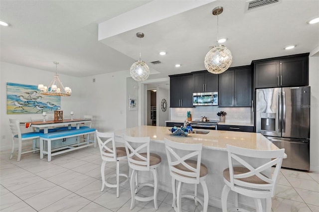 kitchen featuring pendant lighting, tasteful backsplash, sink, a kitchen island with sink, and stainless steel appliances