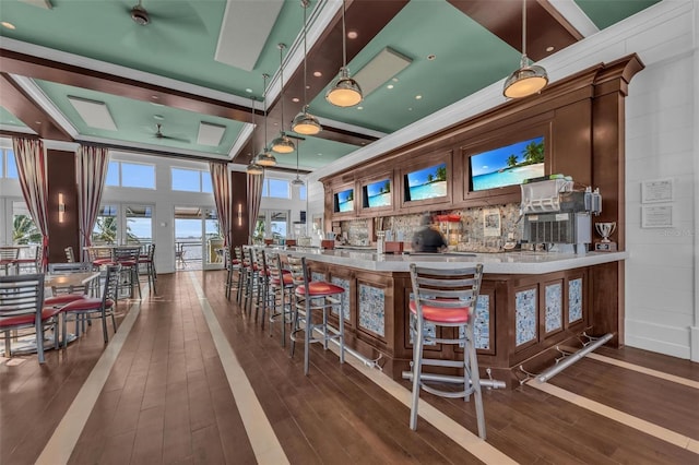 bar with pendant lighting, crown molding, and dark hardwood / wood-style flooring