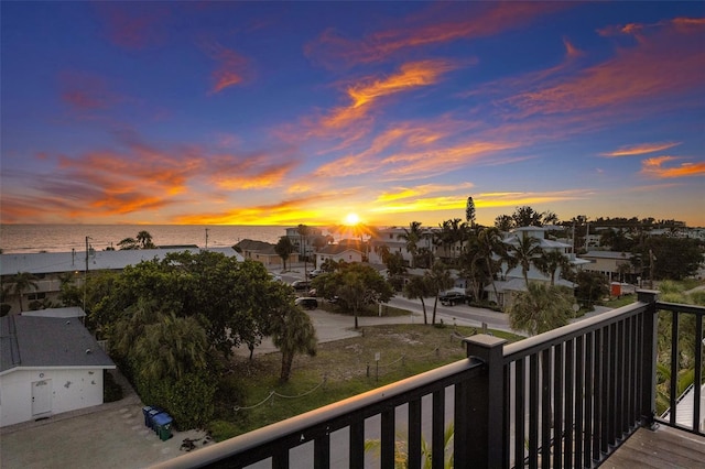 balcony at dusk featuring a water view