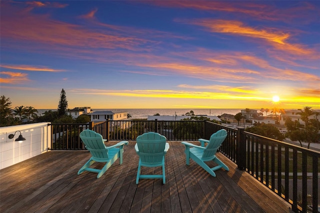 deck at dusk featuring a water view