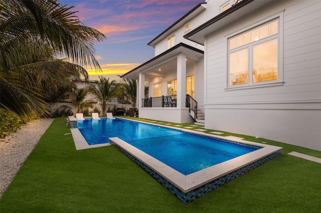 pool at dusk featuring a yard