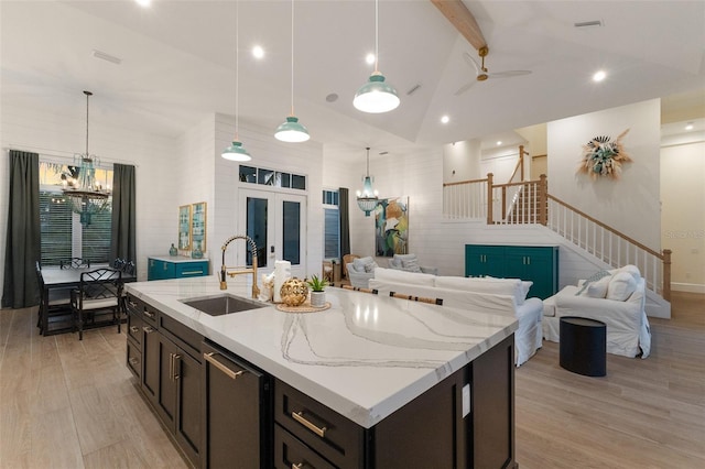 kitchen with sink, lofted ceiling with beams, and an island with sink