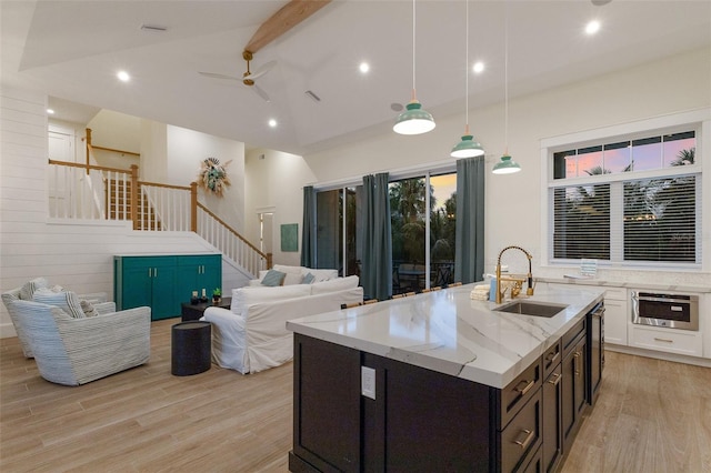 kitchen with sink, light stone counters, light hardwood / wood-style flooring, pendant lighting, and white cabinets