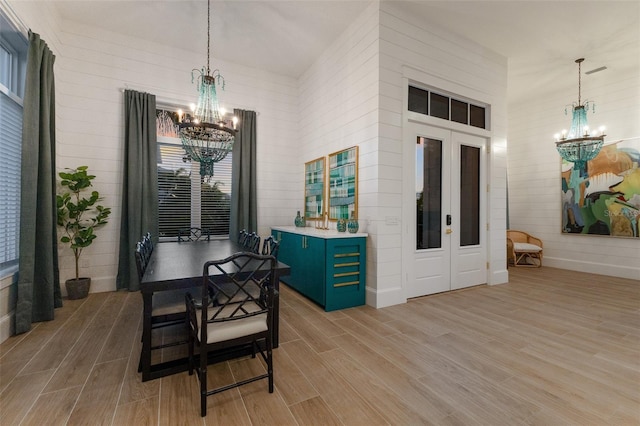 dining room with french doors, a notable chandelier, and light hardwood / wood-style flooring