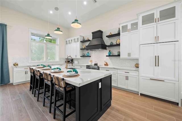 kitchen featuring paneled built in refrigerator, white cabinets, hanging light fixtures, and custom range hood