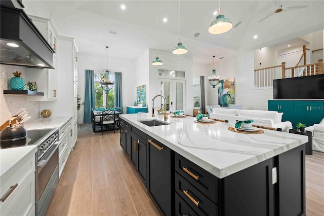 kitchen featuring stainless steel electric range, lofted ceiling, premium range hood, white cabinets, and sink