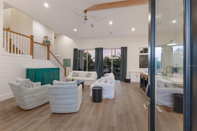 living room featuring beamed ceiling, ceiling fan, light hardwood / wood-style floors, and high vaulted ceiling