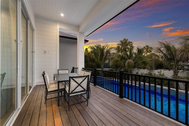 deck at dusk with a fenced in pool