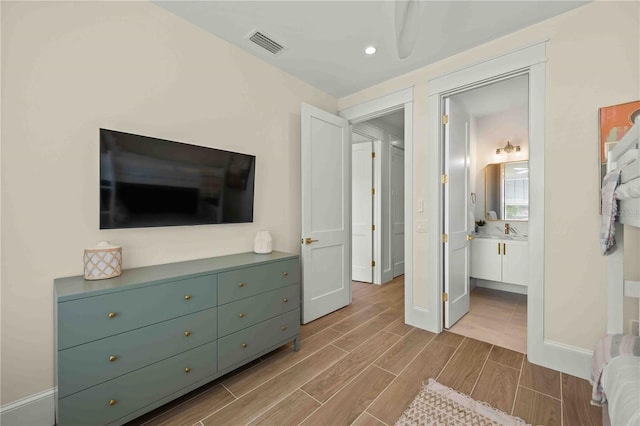 bedroom featuring connected bathroom and sink