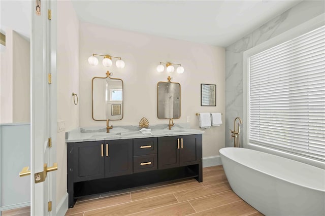 bathroom with a wealth of natural light, a bathtub, and vanity