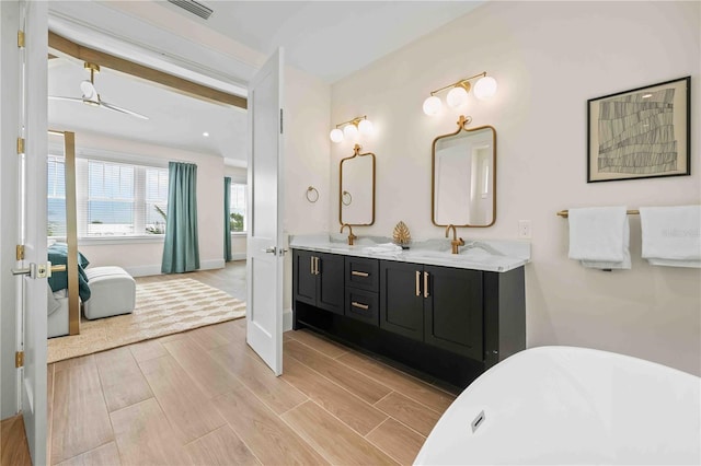 bathroom featuring beam ceiling, ceiling fan, a bathtub, and vanity