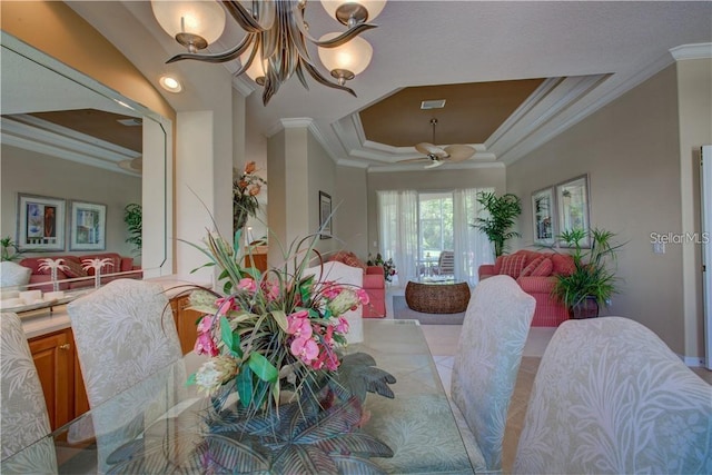 dining space with a raised ceiling, ceiling fan with notable chandelier, and ornamental molding