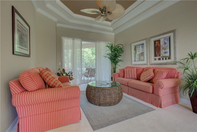 carpeted living room featuring a towering ceiling, a raised ceiling, ceiling fan, and ornamental molding