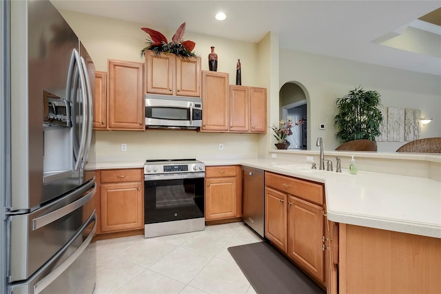 kitchen featuring kitchen peninsula, appliances with stainless steel finishes, light tile patterned floors, and sink