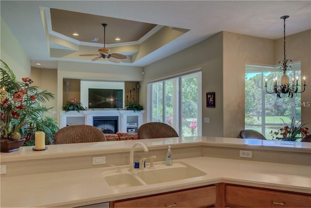 kitchen featuring decorative light fixtures, a tray ceiling, ornamental molding, and sink