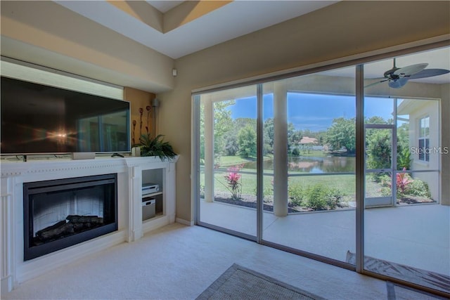 unfurnished living room featuring ceiling fan, a water view, and light colored carpet