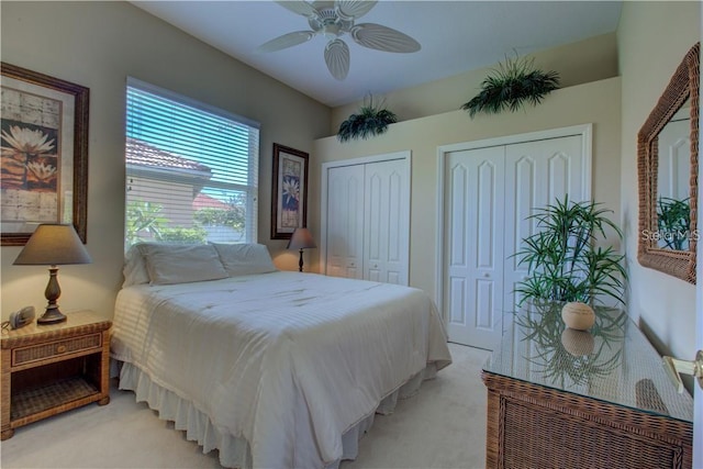 carpeted bedroom featuring ceiling fan and multiple closets