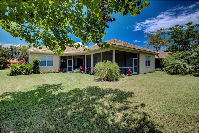 rear view of house featuring a sunroom and a yard