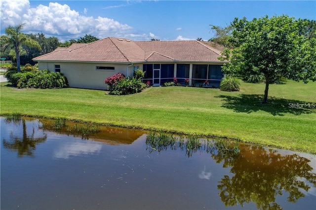 rear view of house with a sunroom, a water view, and a yard