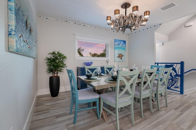 dining area with light hardwood / wood-style flooring and a notable chandelier