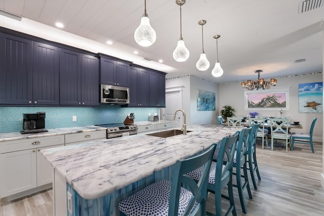 kitchen featuring a kitchen breakfast bar, a kitchen island with sink, pendant lighting, and appliances with stainless steel finishes