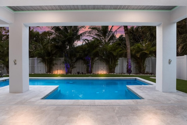 pool at dusk with a patio area