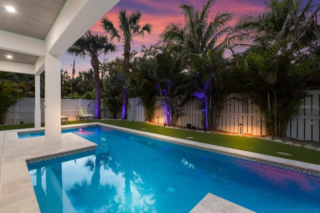 pool at dusk with a lawn and a patio area