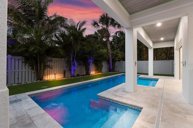 pool at dusk featuring a patio