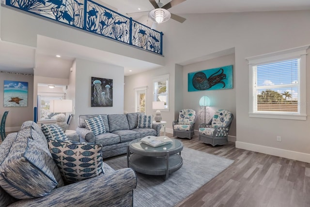 living room featuring hardwood / wood-style floors, a towering ceiling, and ceiling fan