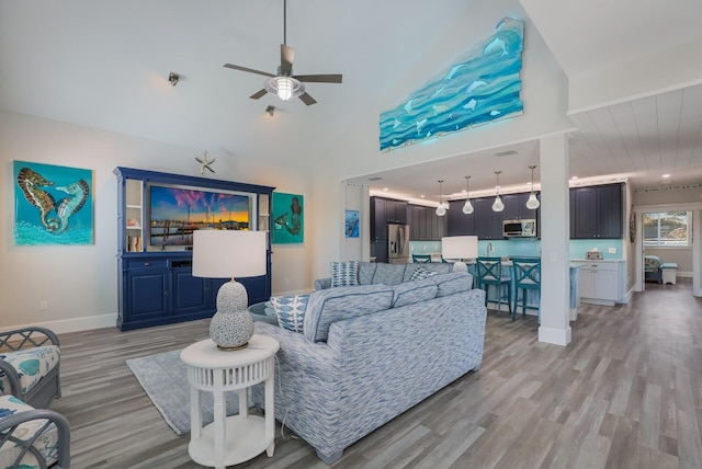 living room with ceiling fan, light hardwood / wood-style flooring, and high vaulted ceiling