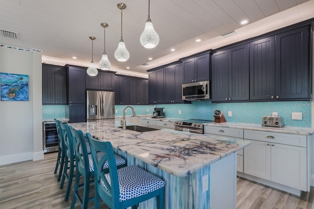 kitchen with a spacious island, decorative light fixtures, sink, and stainless steel appliances