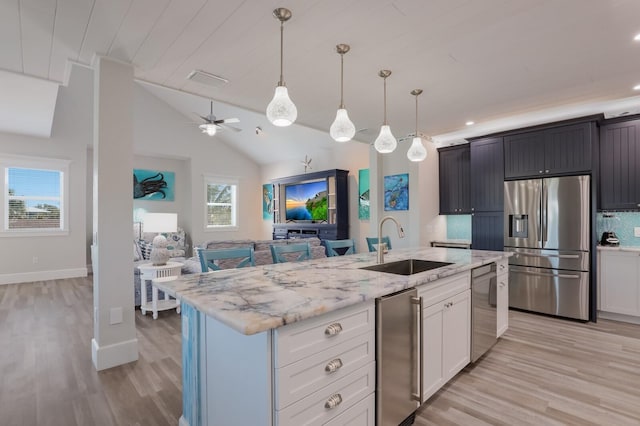 kitchen with sink, hanging light fixtures, a kitchen island with sink, white cabinets, and appliances with stainless steel finishes