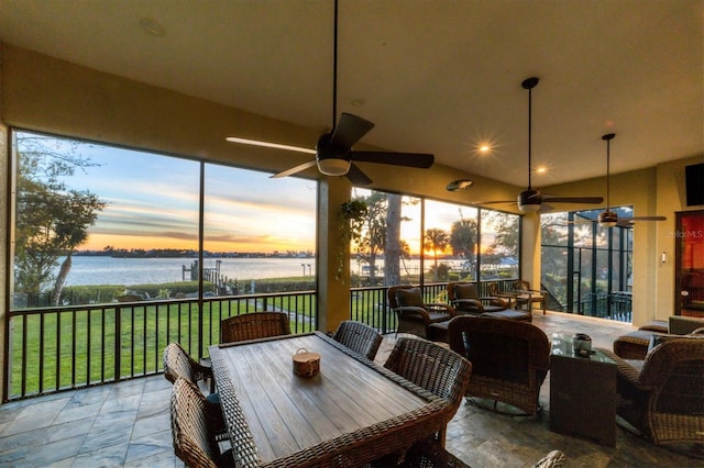 sunroom / solarium with ceiling fan, a water view, and lofted ceiling