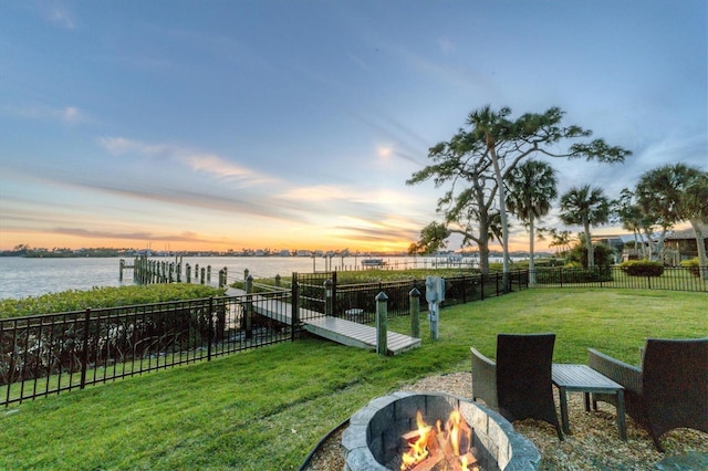 yard at dusk with a water view and an outdoor fire pit