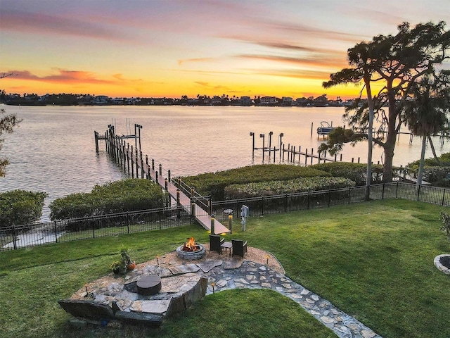 view of dock featuring a yard, a water view, and an outdoor fire pit