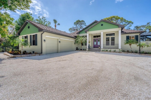 view of front of home featuring covered porch, french doors, and a garage