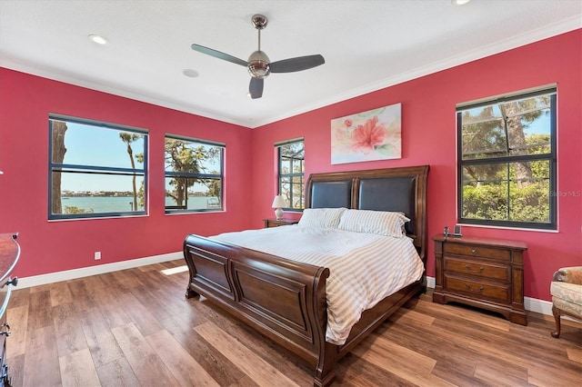 bedroom featuring hardwood / wood-style floors, ceiling fan, crown molding, and multiple windows