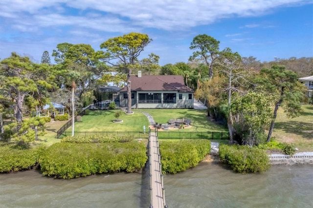 rear view of house with a sunroom, a water view, and a yard